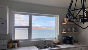 A kitchen with a large window, a sink, and a coffee maker on the counter.