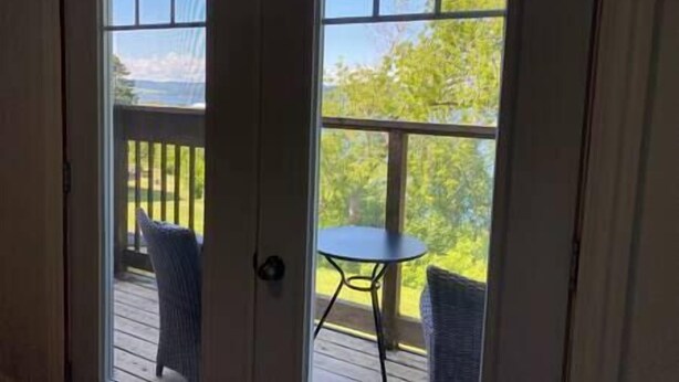 A view from inside a room looking out to a deck with a table and chairs.