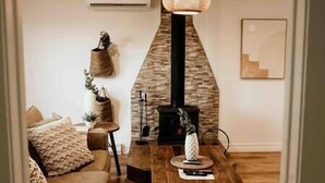 A cozy living room with a stone fireplace, a wooden coffee table, and a comfortable sofa.