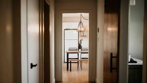 A hallway leading to a dining area with a chandelier.