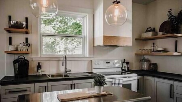 Een moderne keuken met een centraal eiland, roestvrijstalen apparatuur en hanglampen.