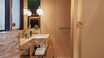 Un baño moderno con encimeras de mármol, un espejo grande y dos lámparas colgantes.