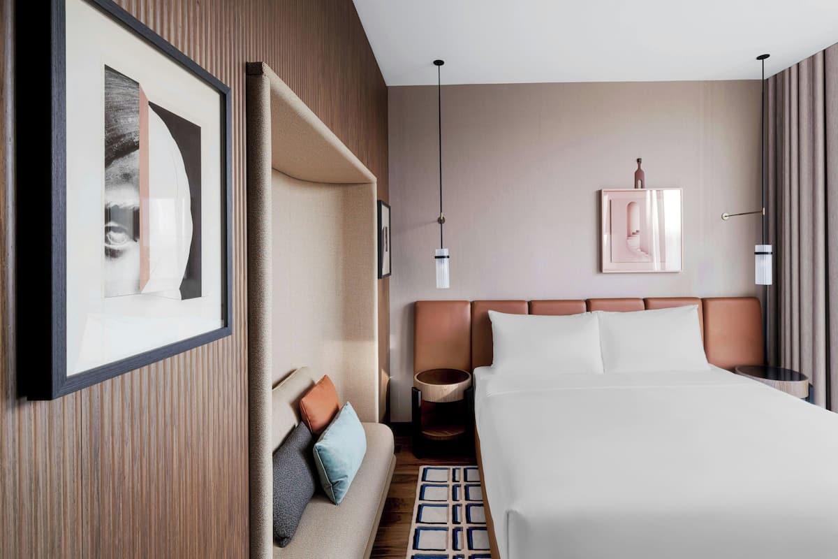 A hotel room with a large bed, a sofa, a small table, and a framed picture on the wall.