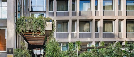 Stunning building with a grid of windows and lush greenery surrounding the entrance.