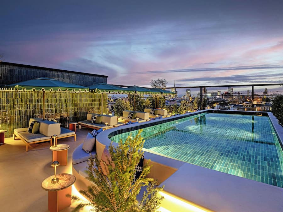 Una piscina al aire libre, sombrillas, sillones reclinables de piscina