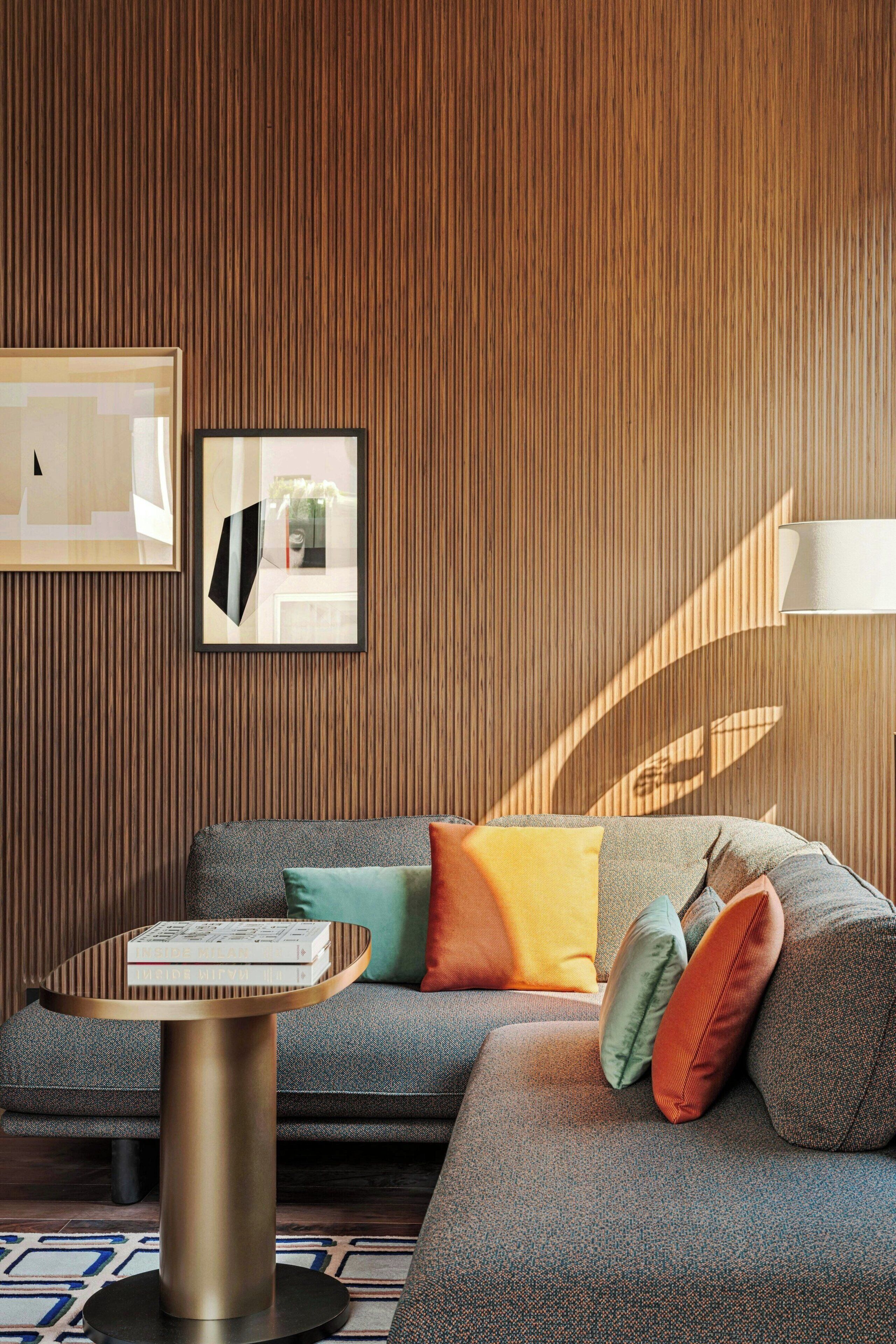 A modern living room with a grey sofa, colorful cushions, a round coffee table, and a framed picture on the wall.