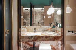 A modern bathroom with a marble countertop, a sink, a mirror, and a towel rack.