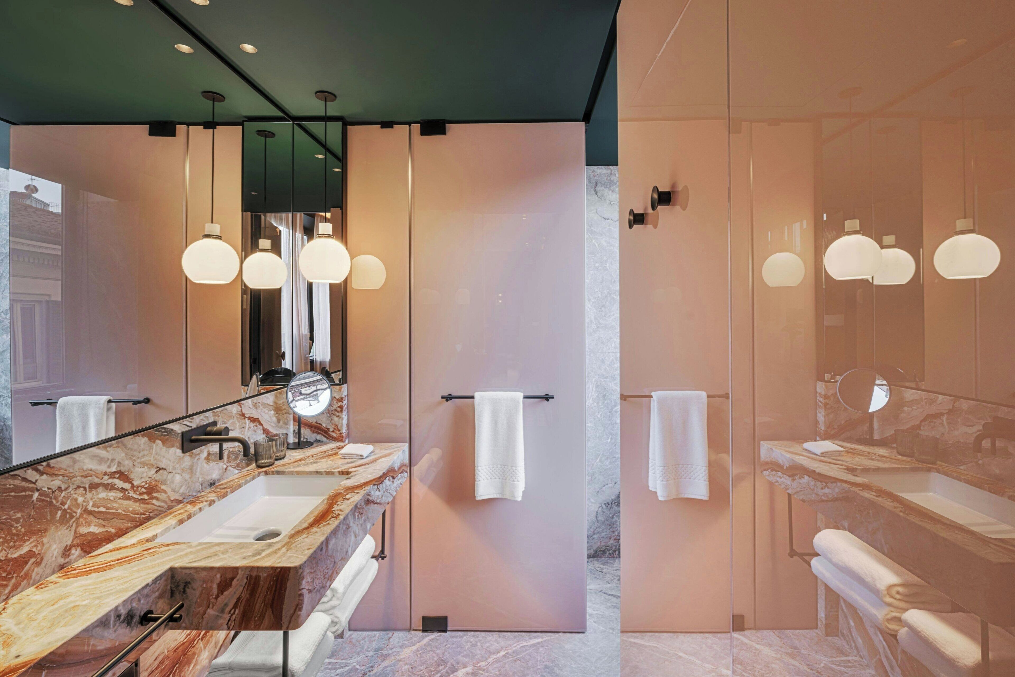 A modern bathroom with a marble vanity, a large mirror, and pendant lighting.