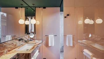 A modern bathroom with a marble vanity, a large mirror, and pendant lighting.