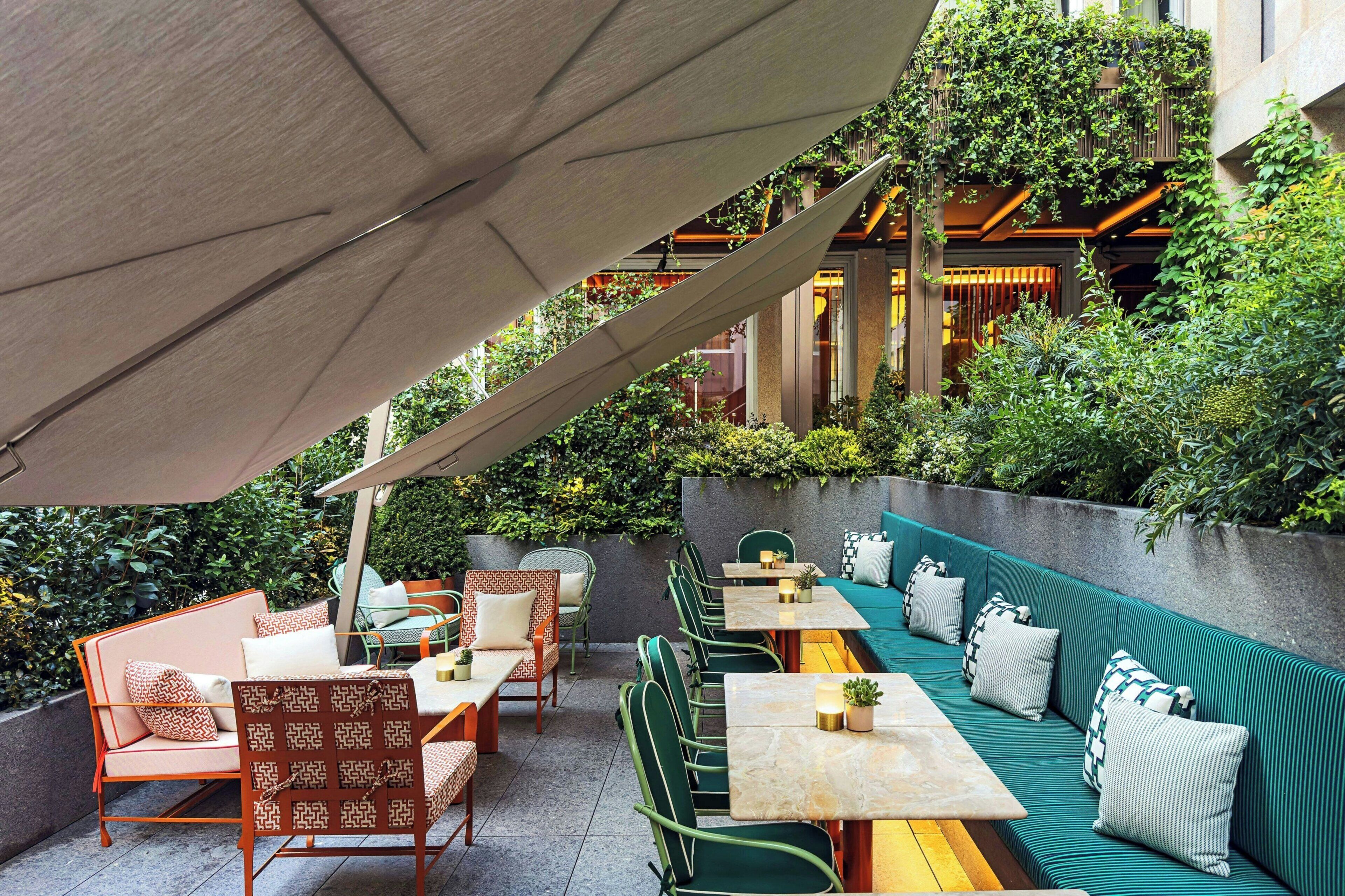 An outdoor seating area with tables and chairs, a green sofa, and a canopy.