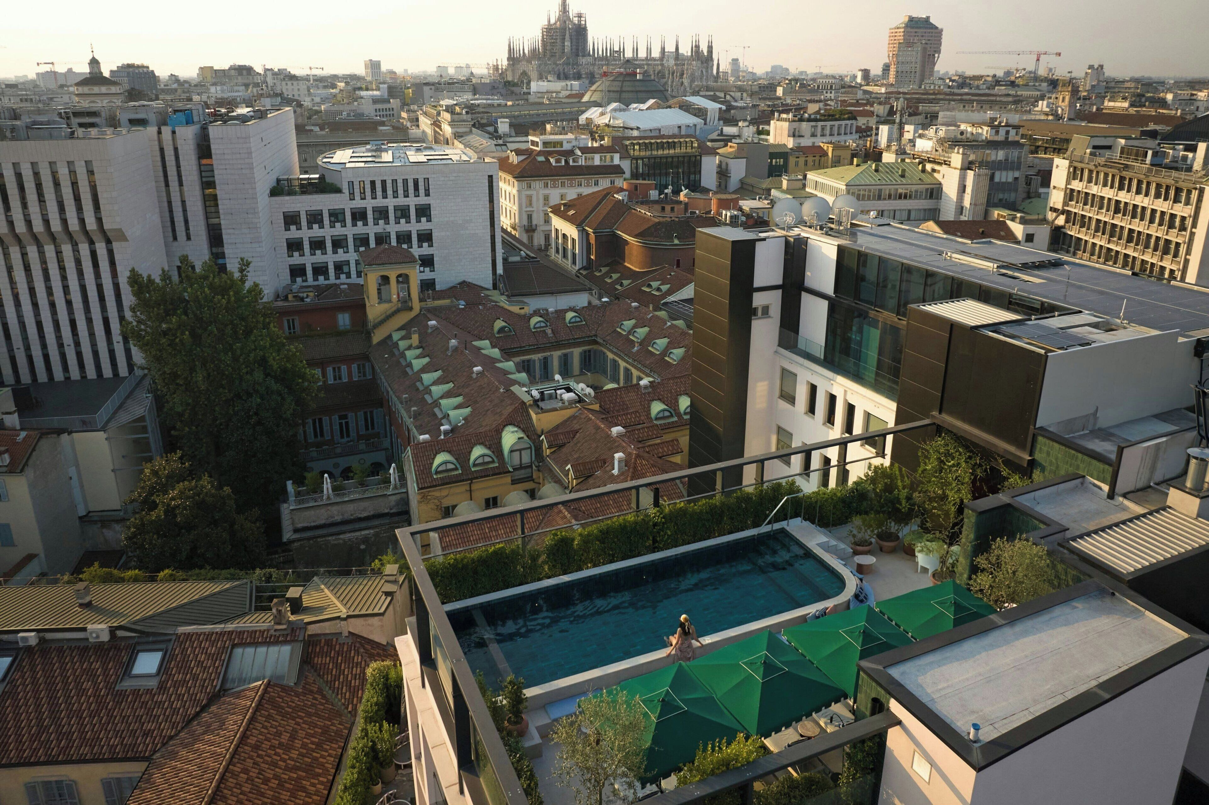 A rooftop swimming pool with a view of the cityscape, including historic and modern buildings.