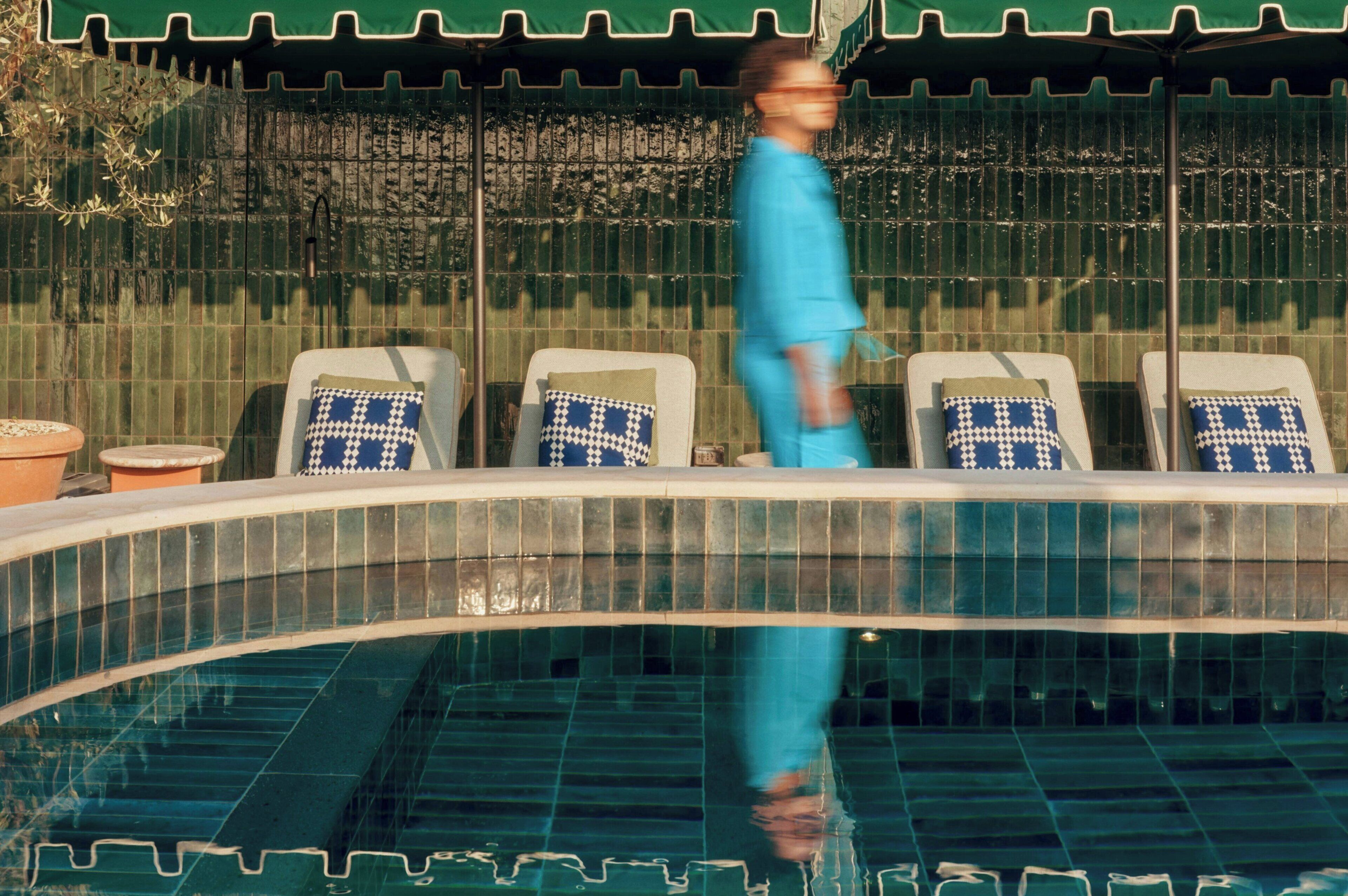 A pool area with lounge chairs and a tiled edge.