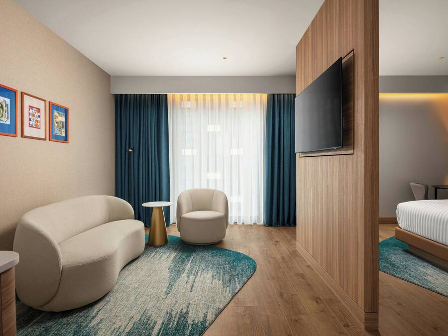 Ein modernes Hotelzimmer mit einer Couch, einem Sessel, einem kleinen runden Tisch und einem Bett.