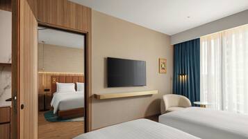 Habitación de hotel con cama, televisor montado en la pared, escritorio y silla.