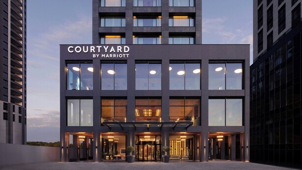 Moderni hotellin sisäänkäynti, jonka yläpuolella on kyltti, jossa lukee: ”Courtyard by Marriott”.