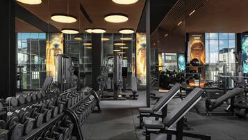 Une salle de sport équipée de divers appareils d’exercice, notamment des haltères, des bancs et des machines de musculation.