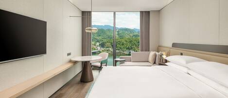 A modern hotel room with a large bed, a flat-screen TV, a small table, and a sofa.