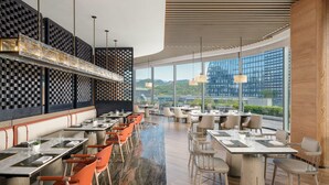 A modern restaurant with a long counter, multiple tables, and chairs. - Lishui Marriott Hotel (Lishui)