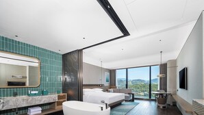 A modern hotel room with a large bed, a bathtub, a vanity with a mirror, and a TV mounted on the wall. - Lishui Marriott Hotel (Lishui)