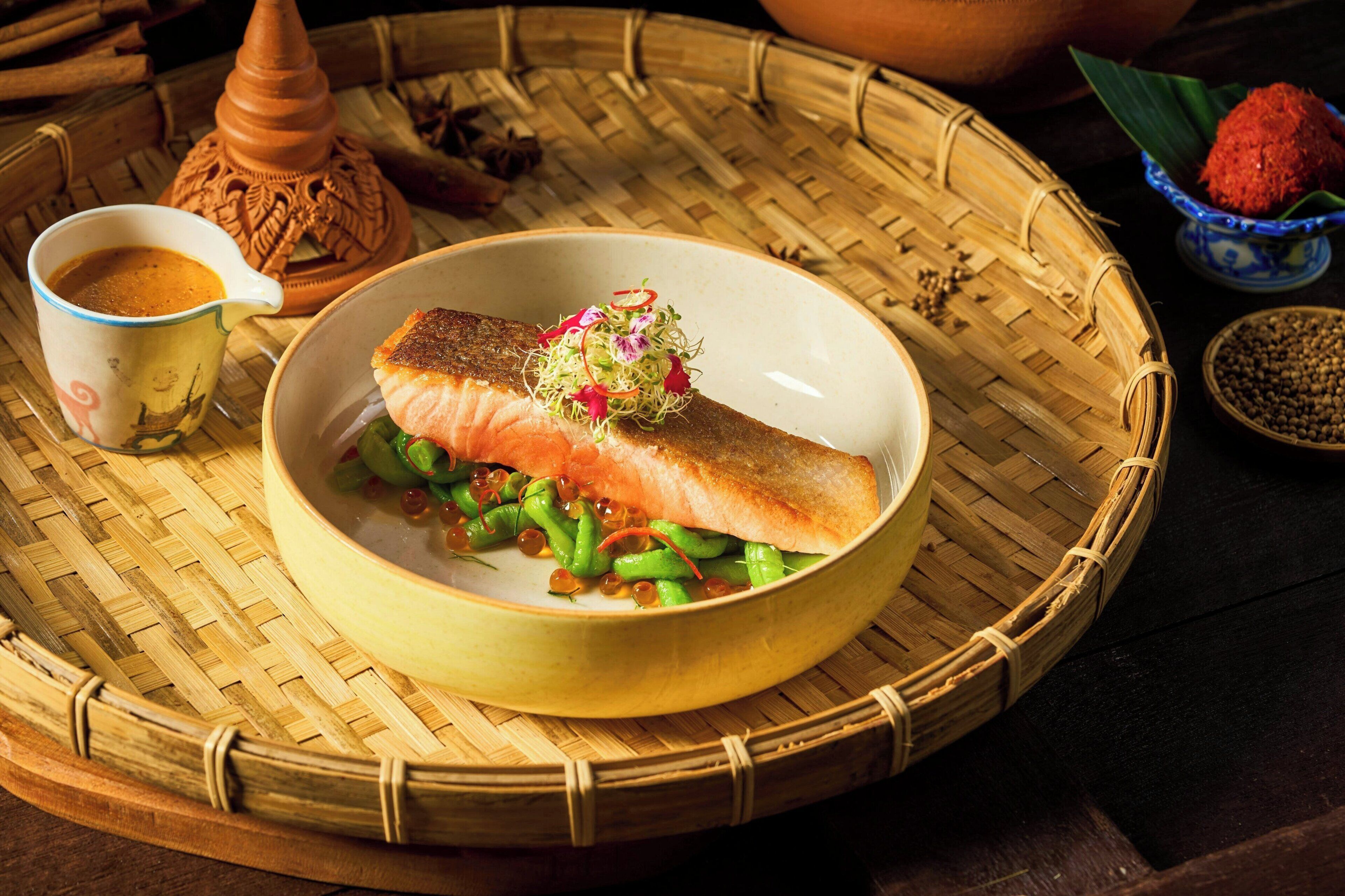Un plat de saumon accompagné de légumes, présenté sur un plat en fibres tressées.