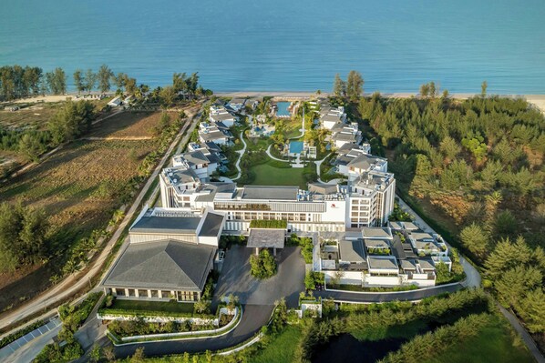 Vista aérea de un resort con un edificio central, una piscina y una playa.