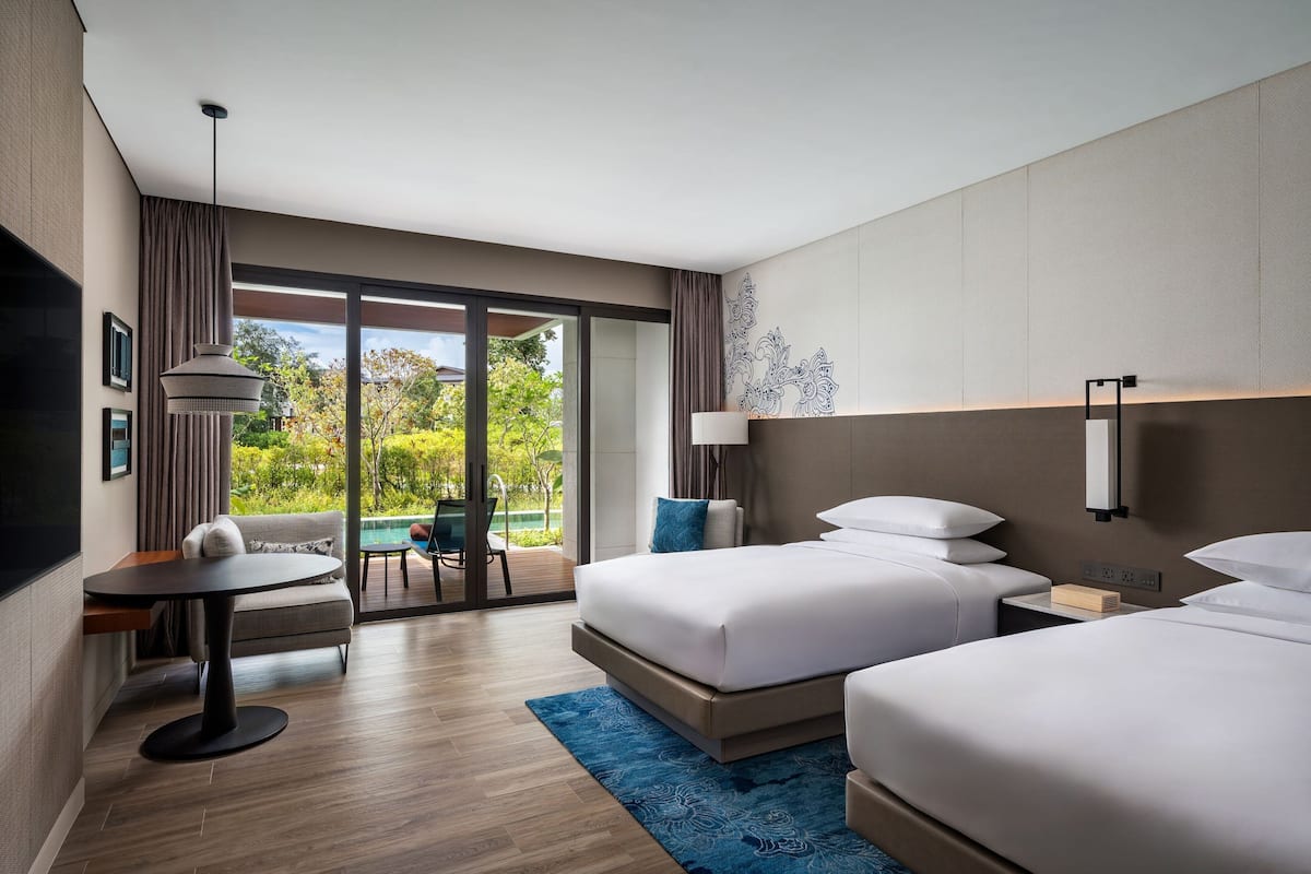 Una habitación de hotel moderna con dos camas, un escritorio y vista a una piscina.