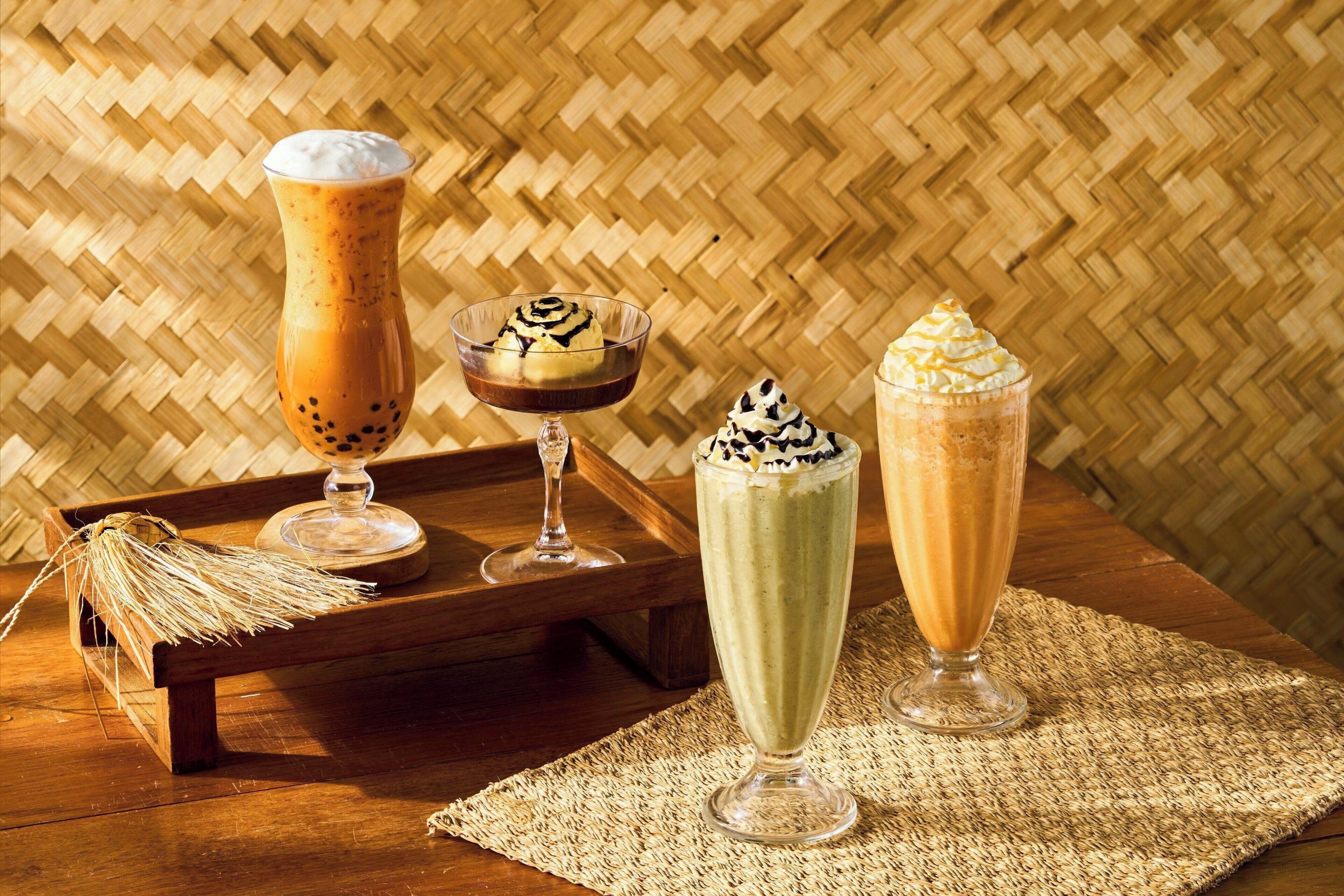 Three dessert drinks on a wooden tray with a woven background.