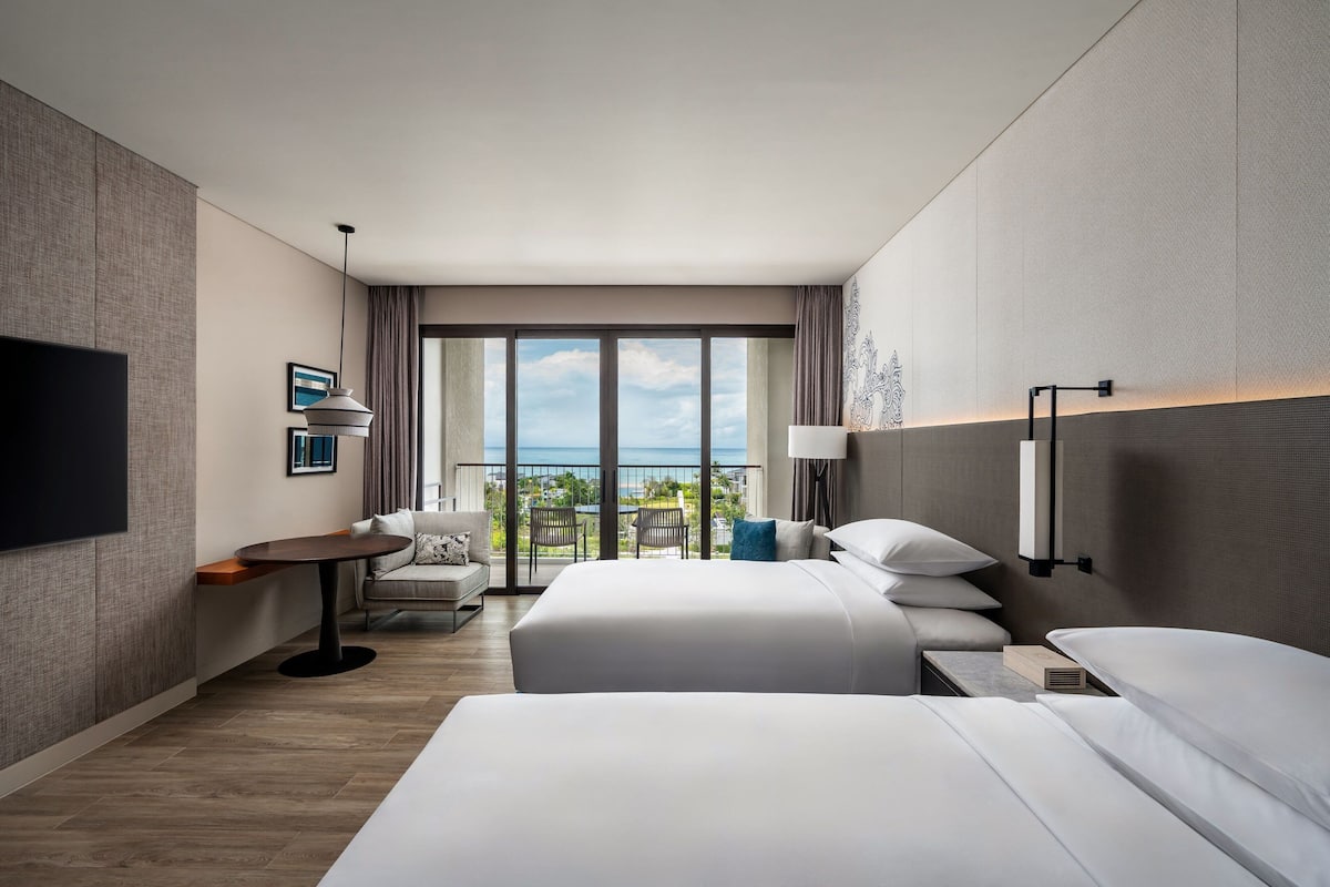 Habitación de hotel con dos camas, un sofá, un televisor, una mesa y vistas al cielo.