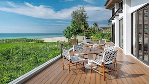 Une terrasse dotée de mobilier d’extérieur, offrant une vue sur une plage et l’océan.