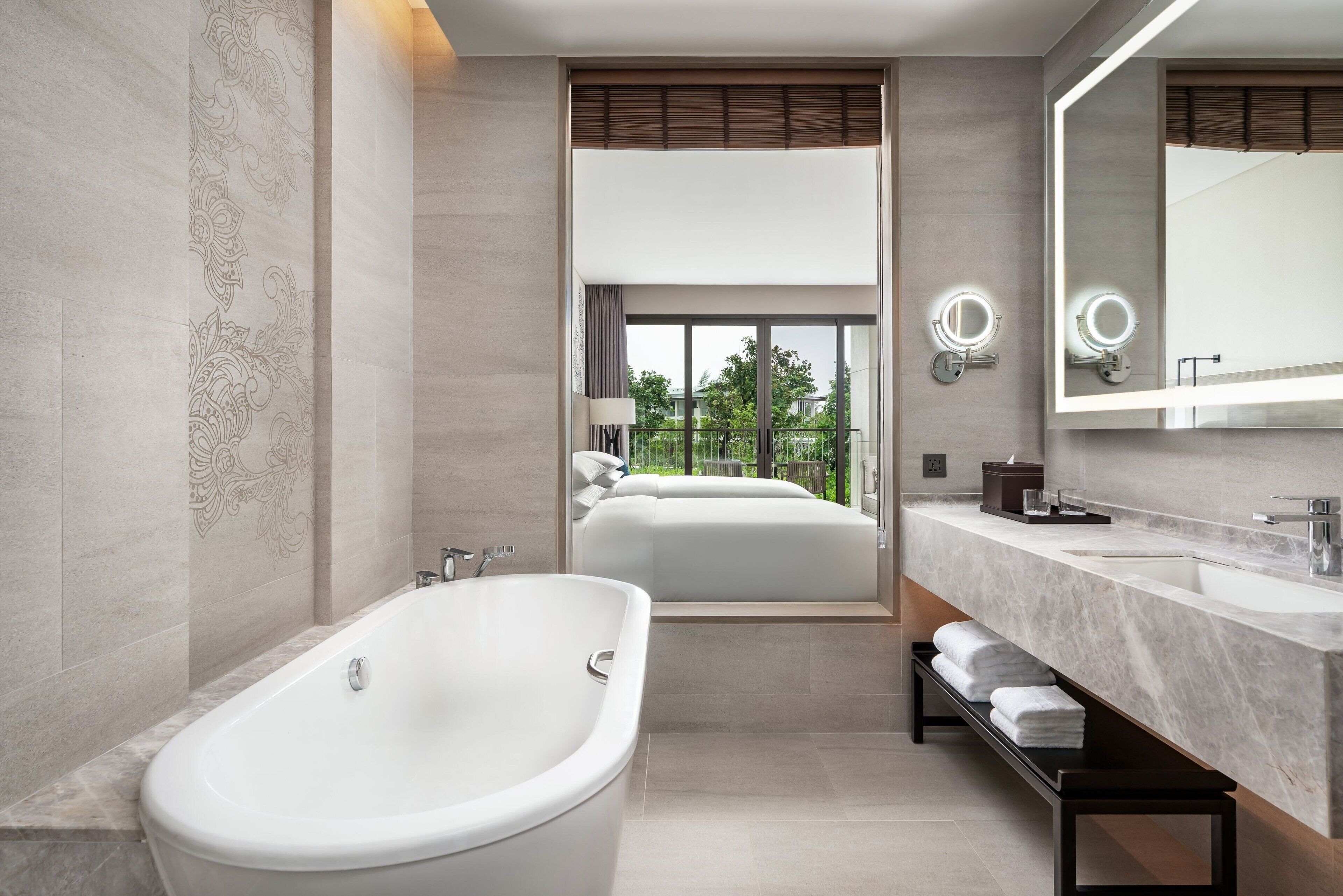 Un bagno moderno con una vasca freestanding, uno specchio grande e una panca con asciugamani.