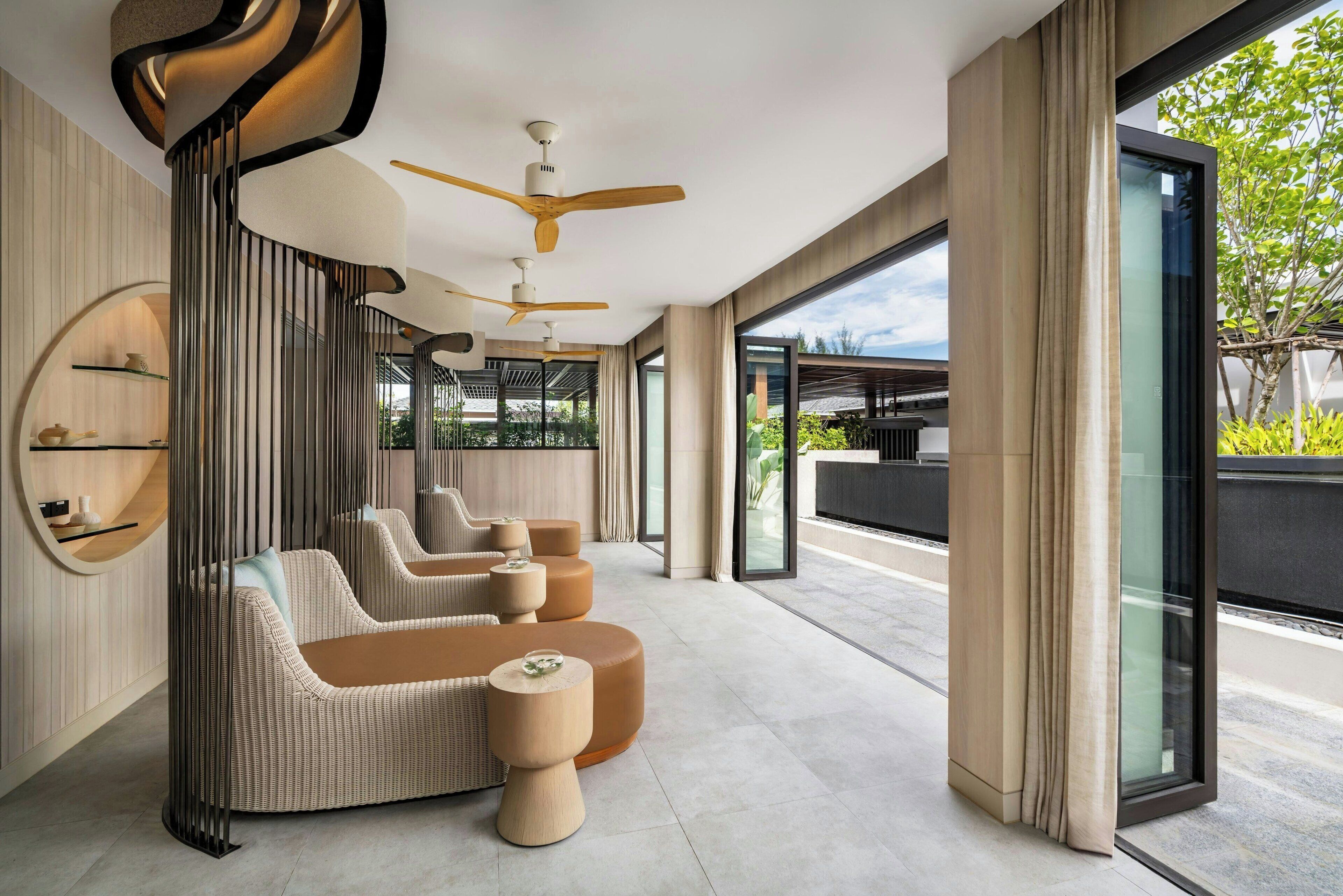 A modern interior with a curved sofa, round ottomans, and ceiling fans.