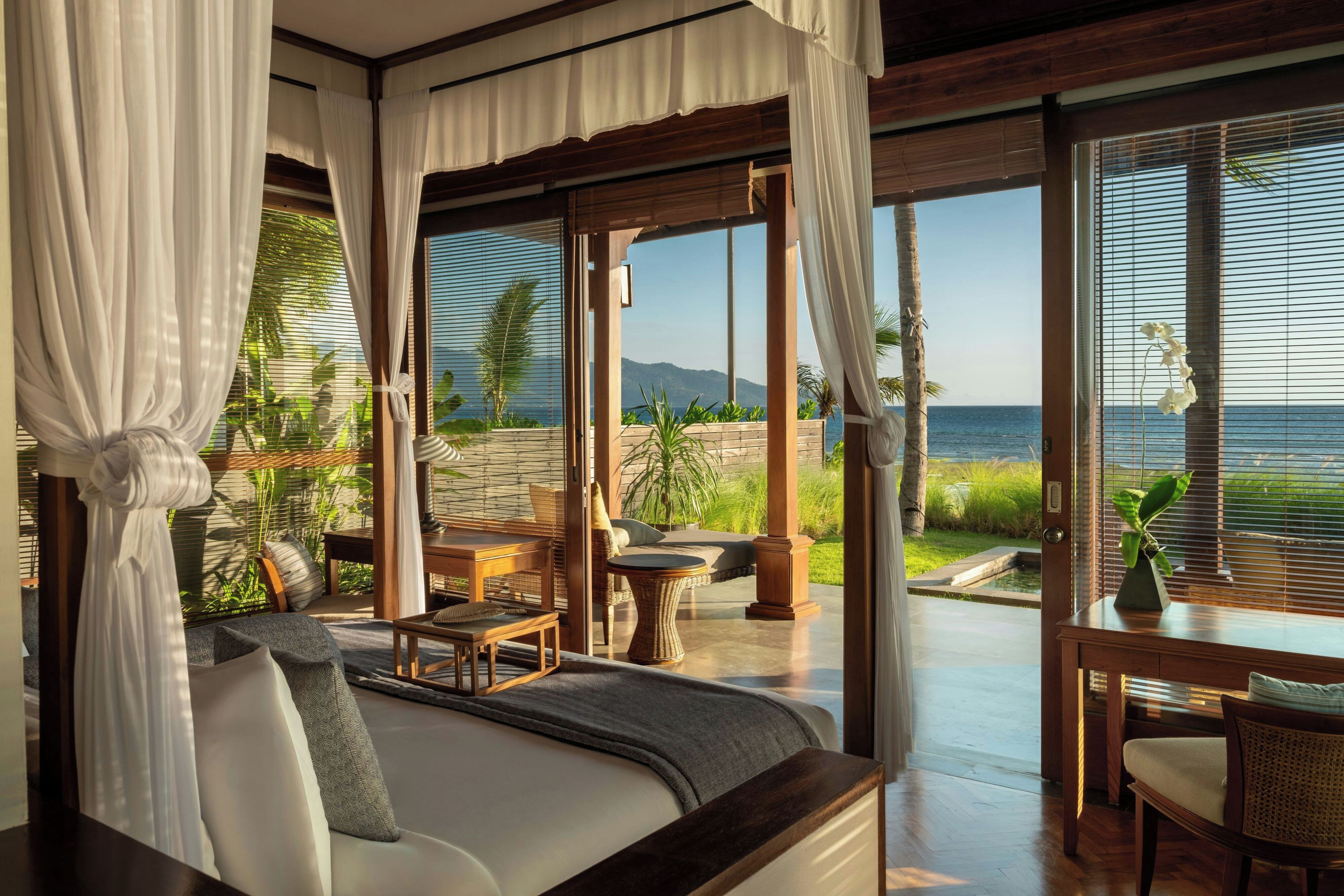Un dormitorio con una cama grande, una zona de estar con una mesa y sillas, y vista al mar.