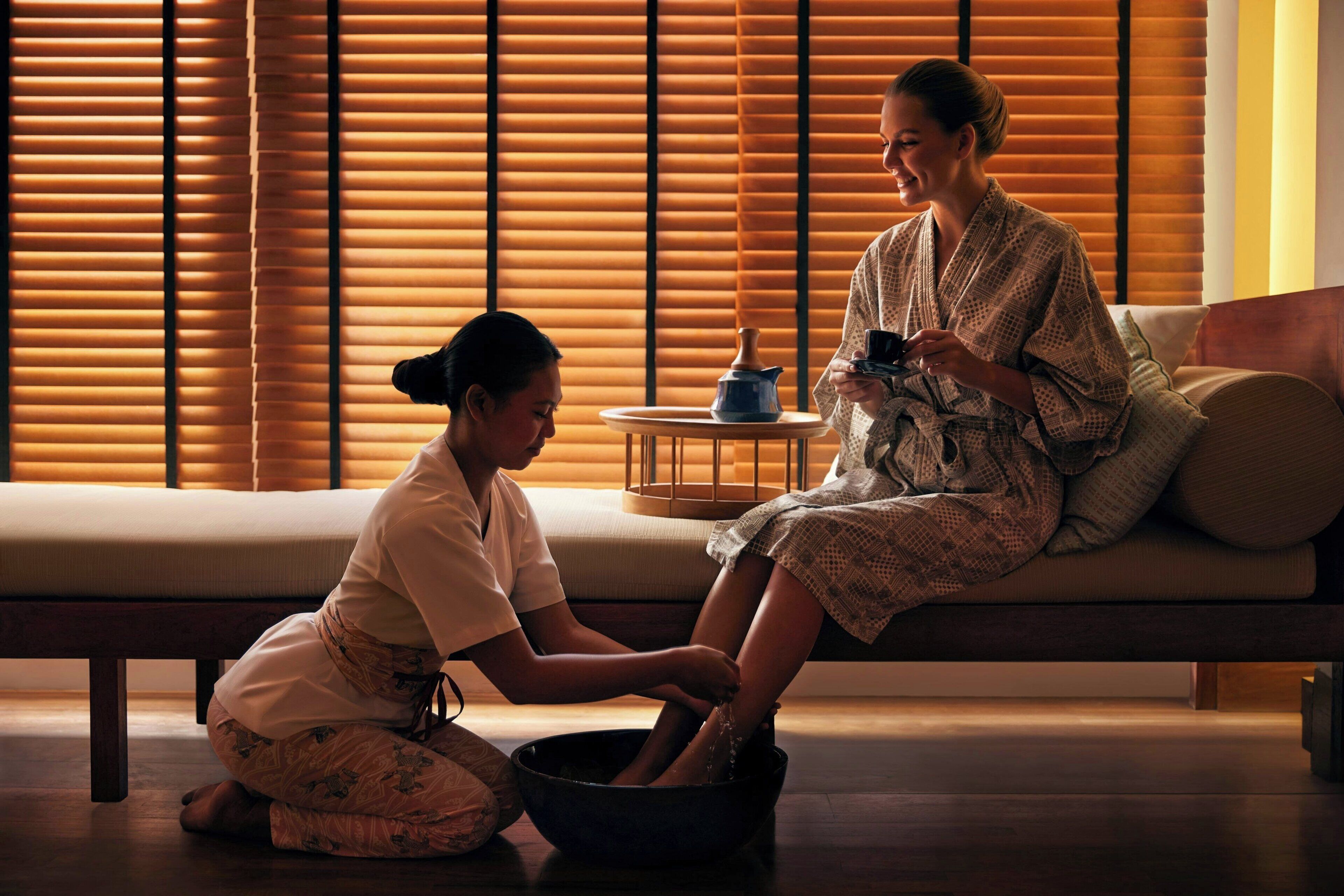 A room with a sofa, a small round table with a teapot, and a bowl.