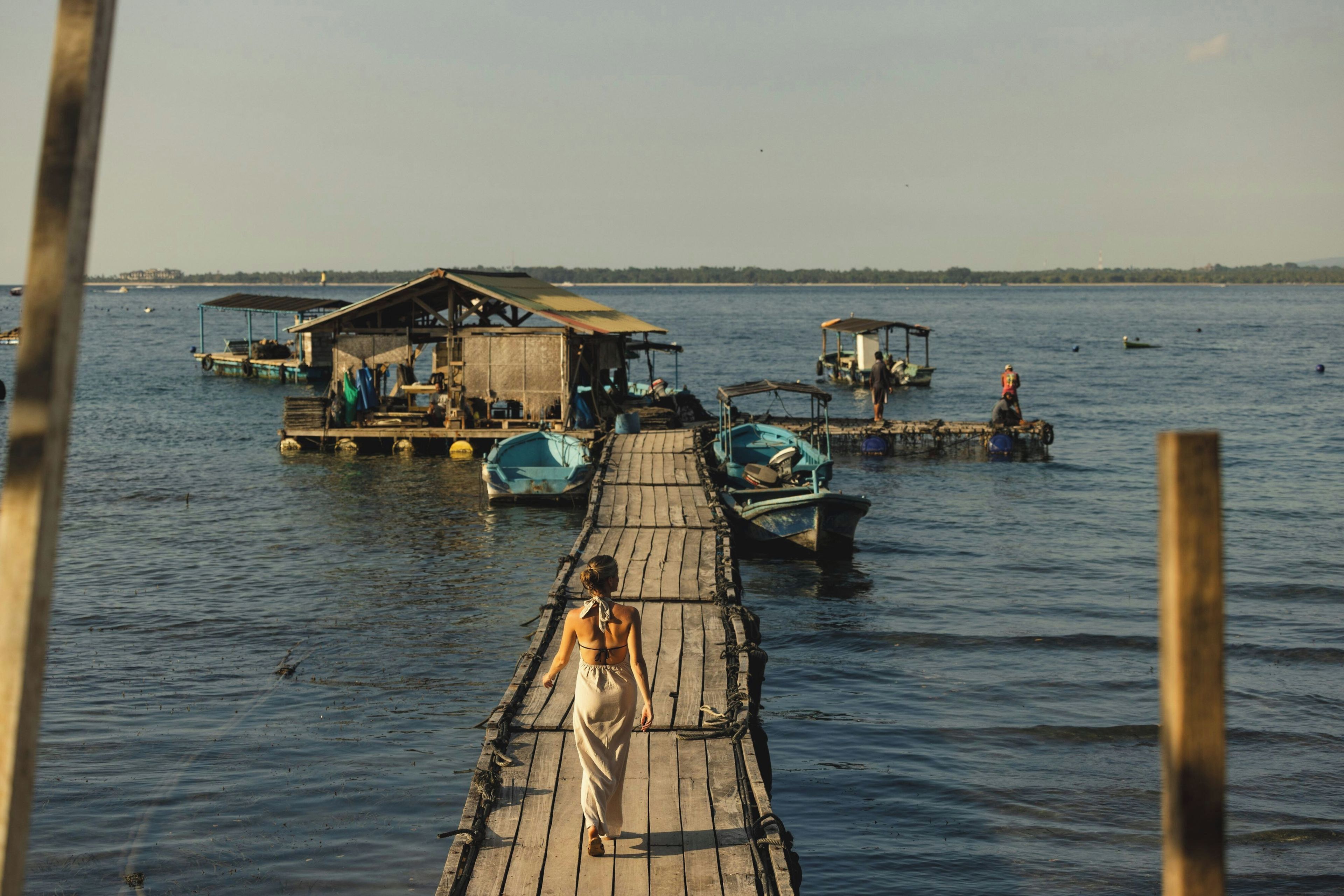 A wooden pier extending into calm water with boats docked at the end.