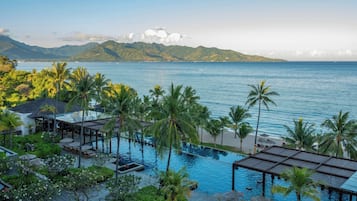 Un resort con piscina, sillas de descanso y palmeras.