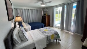 A bedroom with two beds, a ceiling fan, a window with curtains, and a view of the outdoors. - Family Getaway - Private Pool - Sleeps 8 (New Port Richey)