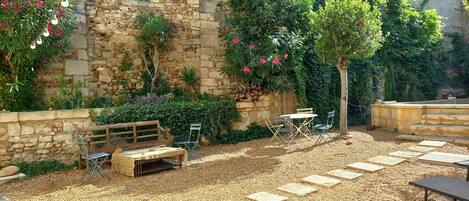 A stone building with a garden patio featuring a table, chairs, and a bench.