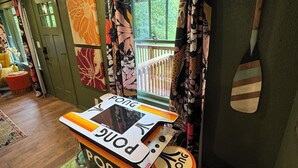 A ping pong table in a room with a green door, colorful curtains, and a wooden floor. - Welcome to The Kitschy Kottage (Rogersville)