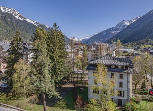 Un pueblo de montaña con arquitectura tradicional, rodeado de picos nevados y bosques densos.