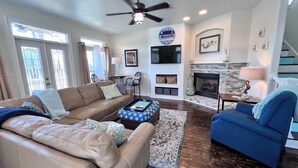 A living room with a beige sofa, a blue armchair, a coffee table, a fireplace, and a clock on the wall. - A Dose of Destin (Destin)
