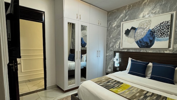 A bedroom with a bed, a wardrobe, a ceiling light, and a marble floor.
