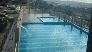 A rooftop swimming pool with a view of the cityscape.