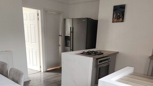 Une cuisine moderne avec des meubles blancs, une cuisinière à gaz et un réfrigérateur.