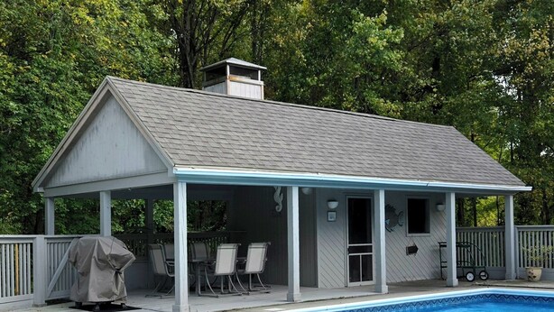 Ein überdachter Poolbereich mit Pavillon, Stühlen und Grill.