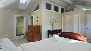 Ein Schlafzimmer mit einem Bett, einem Schminktisch, einem Nachttisch und einem Fenster mit Jalousien.