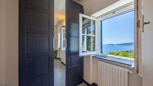 A hallway with a dark wooden door, a window with a view of the sea, and a radiator. - VILLA DUFOUR 2 - Luxury, Swimming Pool, and Dream View (Zoagli)
