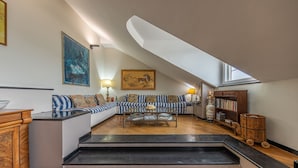 Een woonkamer in loftstijl met een hoge nok, een zithoek, een salontafel en een boekenkast.