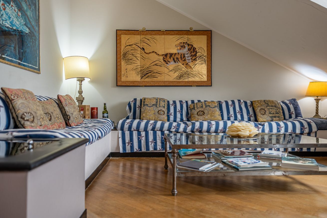 Ein Wohnzimmer mit gestreiften Sofas, einem Glastisch und einem gerahmten Kunstwerk mit einem Tiger.