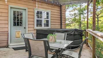 Katettu terassi, jossa on pöytä ja tuoleja, grilli ja ovi, jossa on ikkuna.