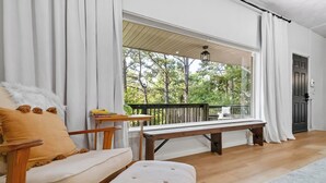 A room with a wooden bench, a cushioned bench, and a table with books.